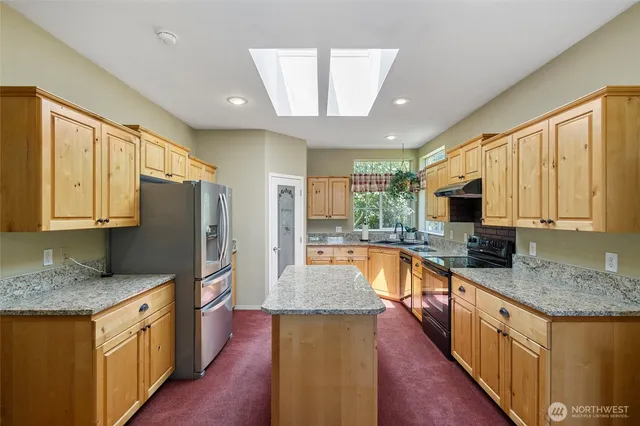 a large kitchen with stainless steel appliances granite countertop a sink refrigerator and cabinets