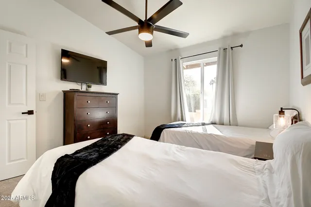 a bedroom with a bed a flat screen tv and a chandelier