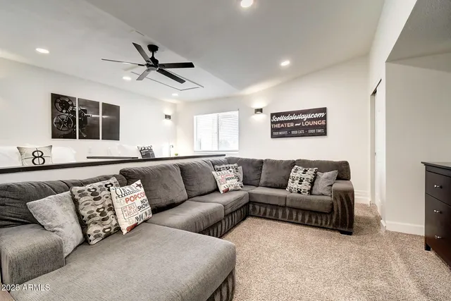 a living room with a flat screen tv and a ceiling fan