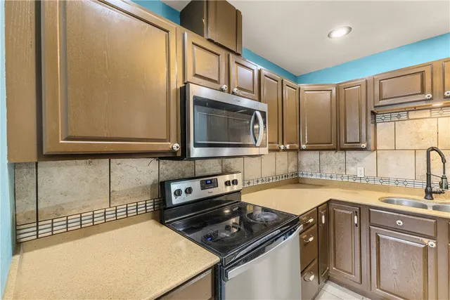 a kitchen with stainless steel appliances a sink a stove cabinets and a counter top space