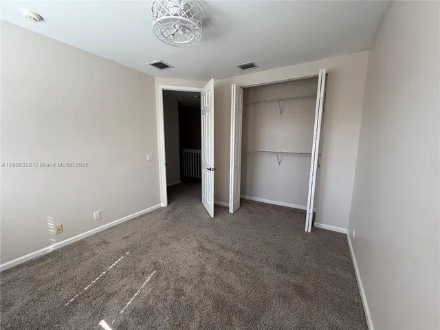 an empty room with a ceiling fan and carpet