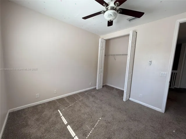 an empty room with closet and a ceiling fan