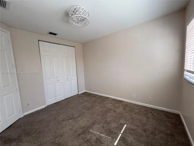 an empty room with a ceiling fan and a window