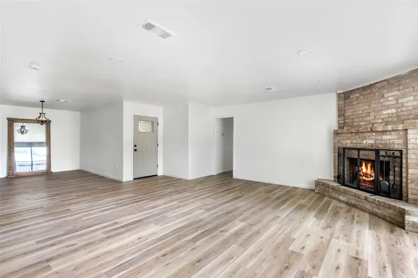 an empty room with wooden floor fireplace and windows