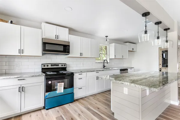a kitchen with stainless steel appliances granite countertop a sink stove and microwave