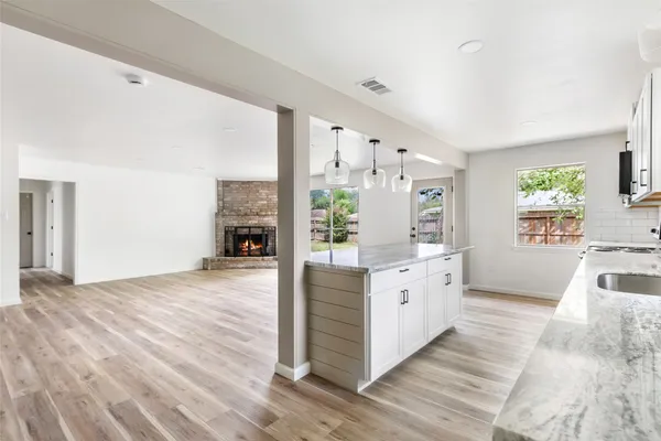 a large white kitchen with granite countertop a large counter top and wooden floors