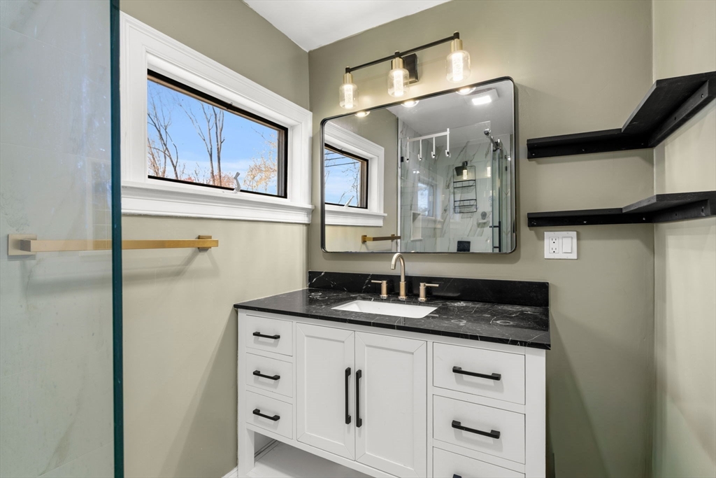 271 Broadway Haverhill, MA 01832 - Photo 19 of 41 a bathroom with a granite countertop sink a mirror a vanity and a shower