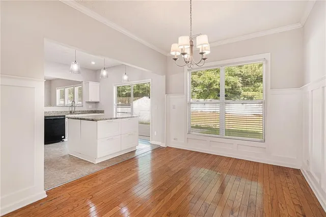 a view of an empty room and kitchen with wooden floor