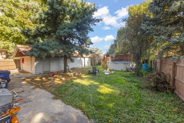 a backyard of a house with table and chairs under an umbrella