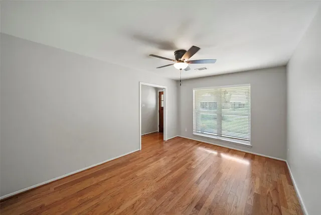 a view of an empty room with wooden floor and a window
