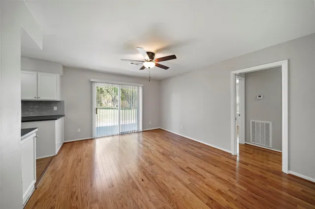 a view of empty room with wooden floor and fan