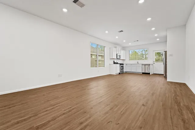 a view of empty room with wooden floor and windows