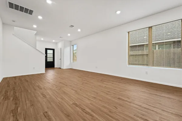 an empty room with wooden floor and windows