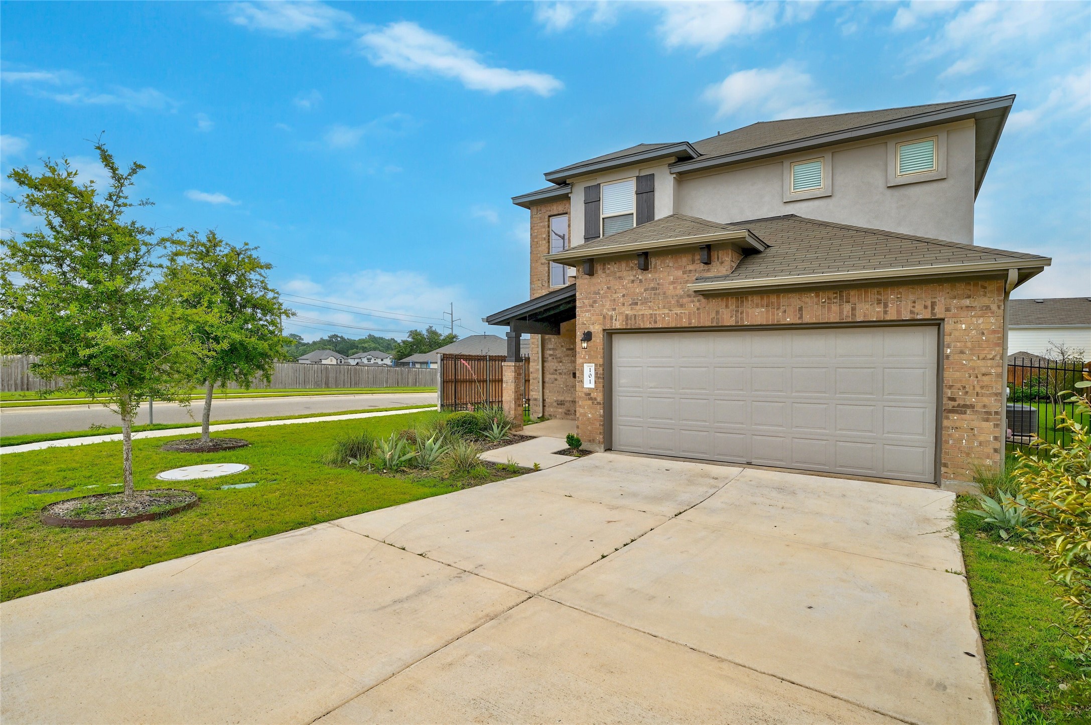 101 Lambert Street Leander, TX 78641 - Photo 3 of 33 A well-maintained facade features a spacious driveway leading to an attached garage, framed by verdant landscaping.