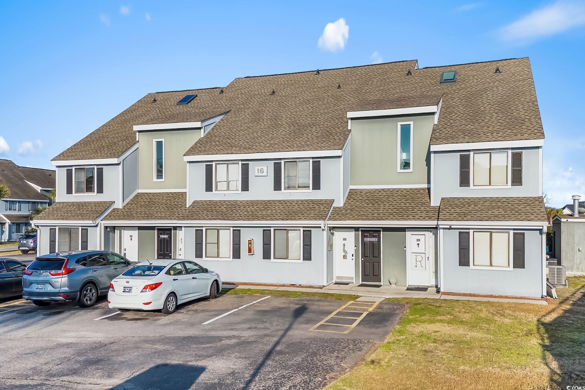 View of front facade with roof with shingles and uncovered parking