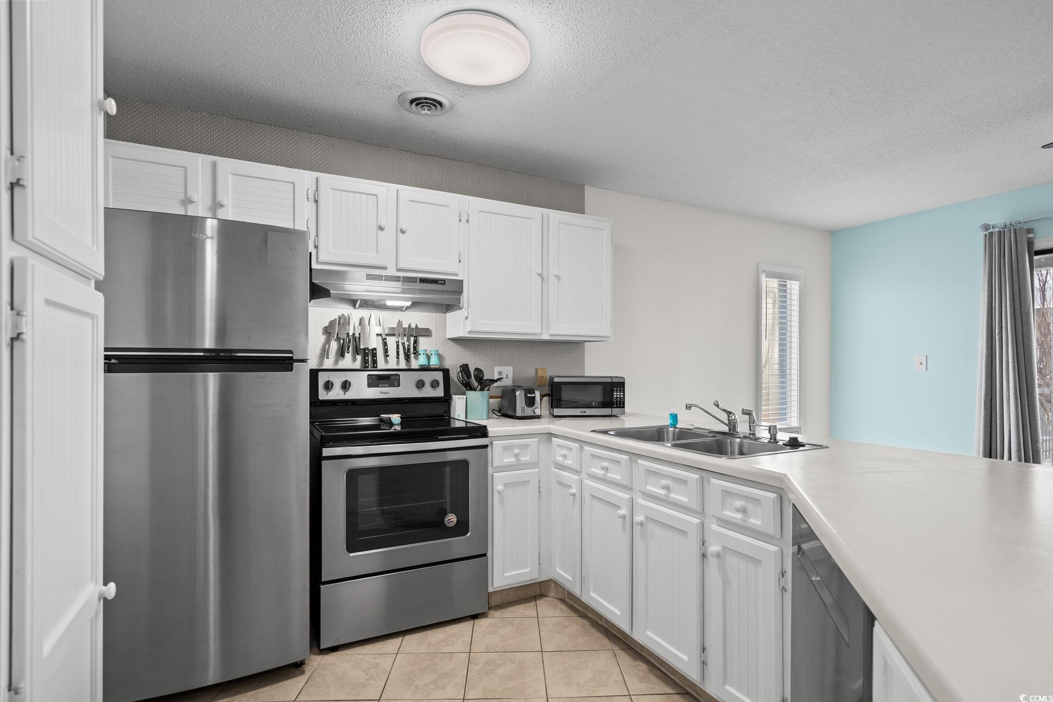 1890 Colony Drive, Unit 16I Myrtle Beach, SC 29575 - Photo 11 of 35 Kitchen featuring stainless steel appliances, a textured ceiling, light countertops, white cabinets, and light tile patterned floors
