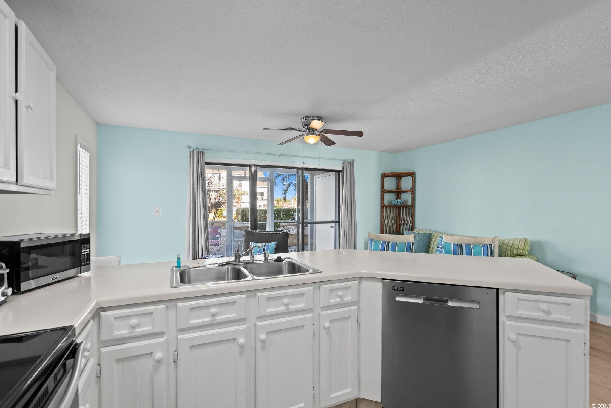 1890 Colony Drive, Unit 16I Myrtle Beach, SC 29575 - Photo 14 of 35 Kitchen with stainless steel appliances, white cabinetry, light countertops, a peninsula, and light wood finished floors