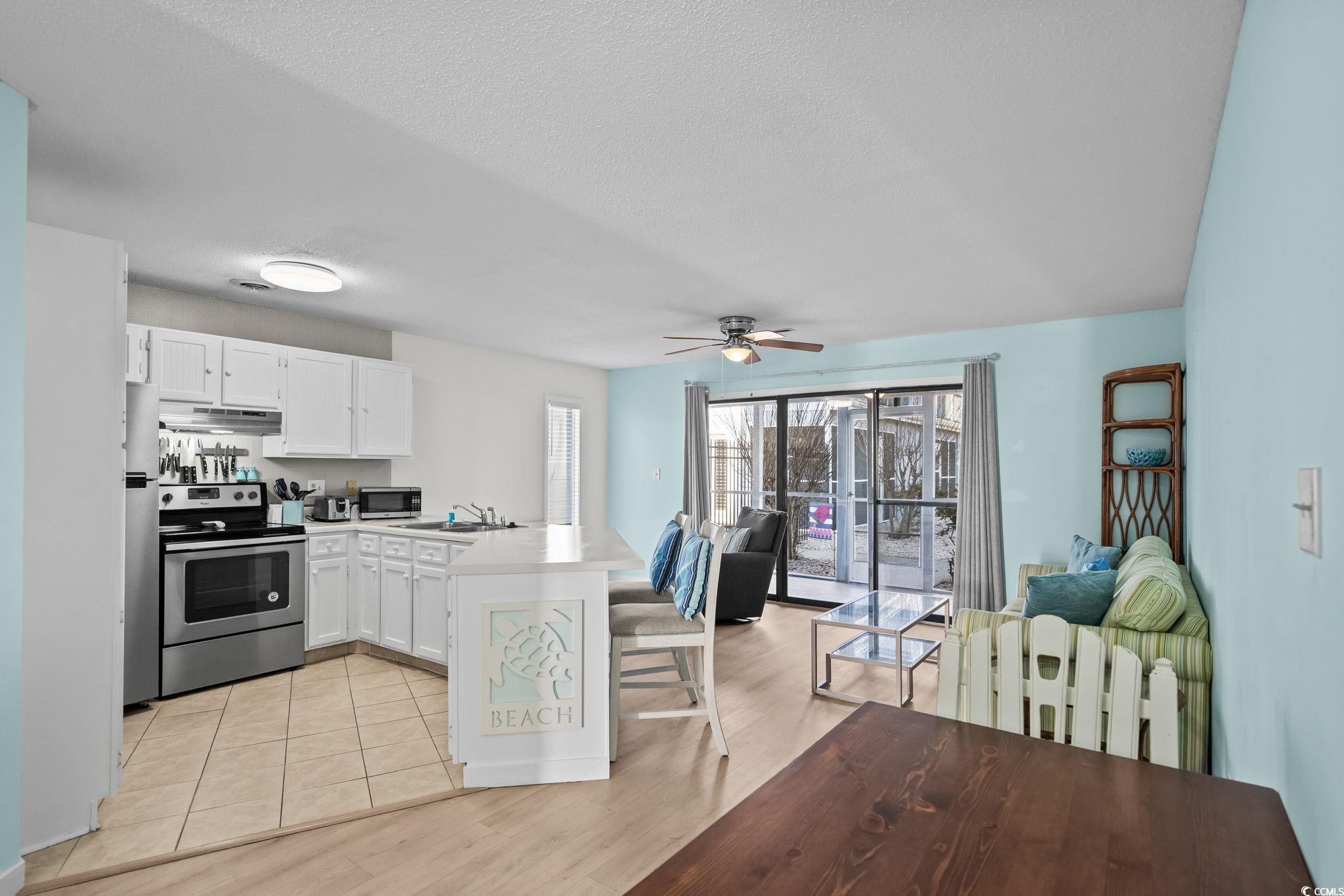 1890 Colony Drive, Unit 16I Myrtle Beach, SC 29575 - Photo 16 of 35 Kitchen featuring a peninsula, a kitchen breakfast bar, appliances with stainless steel finishes, white cabinets, and light countertops