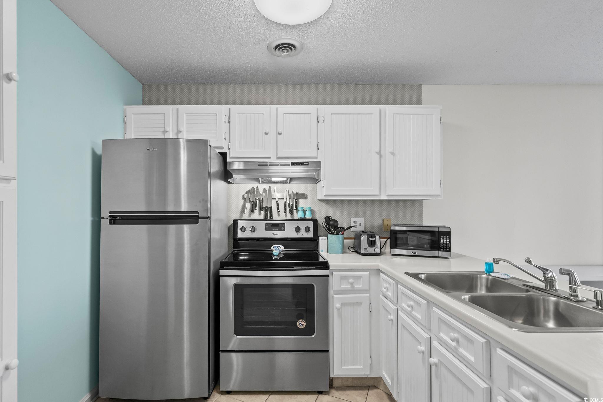 1890 Colony Drive, Unit 16I Myrtle Beach, SC 29575 - Photo 6 of 35 Kitchen featuring appliances with stainless steel finishes, light countertops, white cabinets, a textured ceiling, and under cabinet range hood