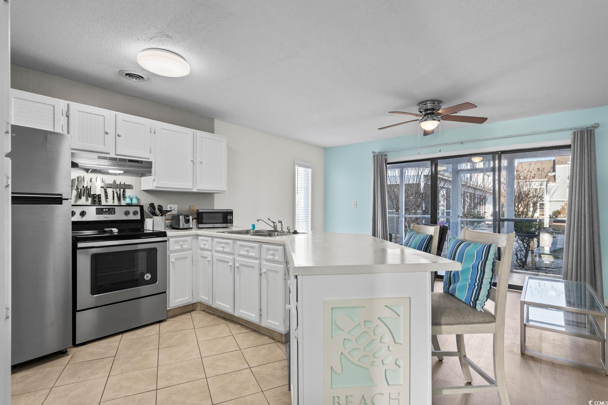 1890 Colony Drive, Unit 16I Myrtle Beach, SC 29575 - Photo 7 of 35 Kitchen featuring a peninsula, stainless steel appliances, light countertops, white cabinetry, and a breakfast bar area