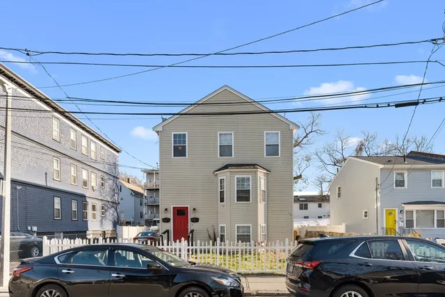 a front view of a building with cars parked
