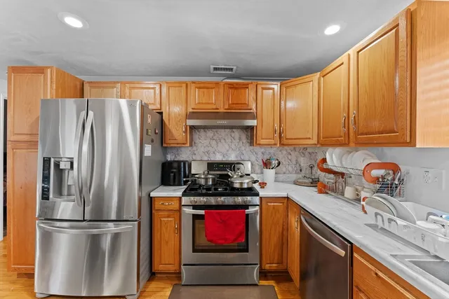 a kitchen with stainless steel appliances granite countertop a refrigerator sink and stove