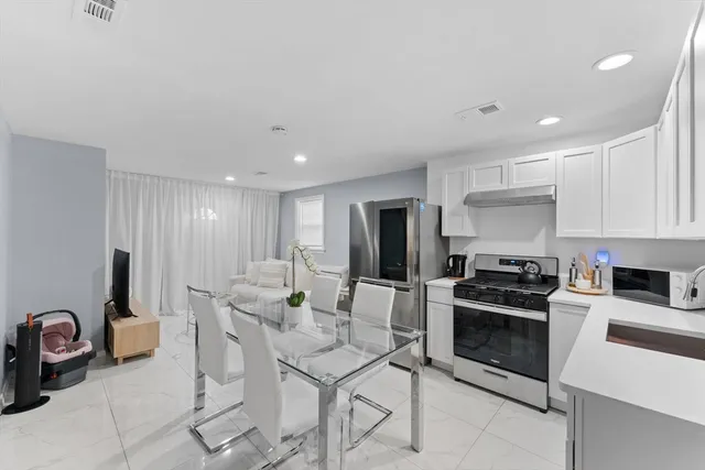 a kitchen with stainless steel appliances kitchen island granite countertop a table chairs sink and cabinets