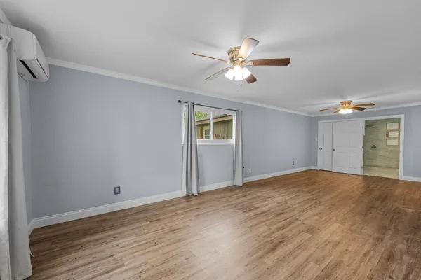 a view of a big room with wooden floor chandelier fan and windows