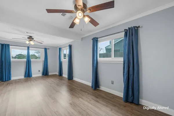 an empty room with wooden floor chandelier fan and windows