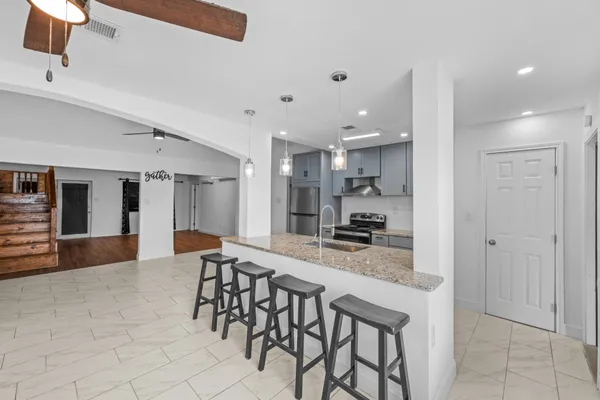 a kitchen with stainless steel appliances kitchen island granite countertop a table chairs sink and cabinets
