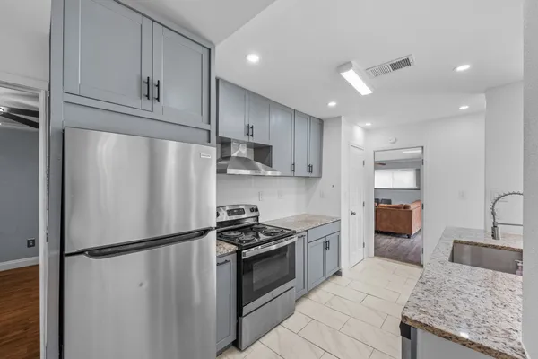 a kitchen with granite countertop stainless steel appliances sink stove microwave and cabinets