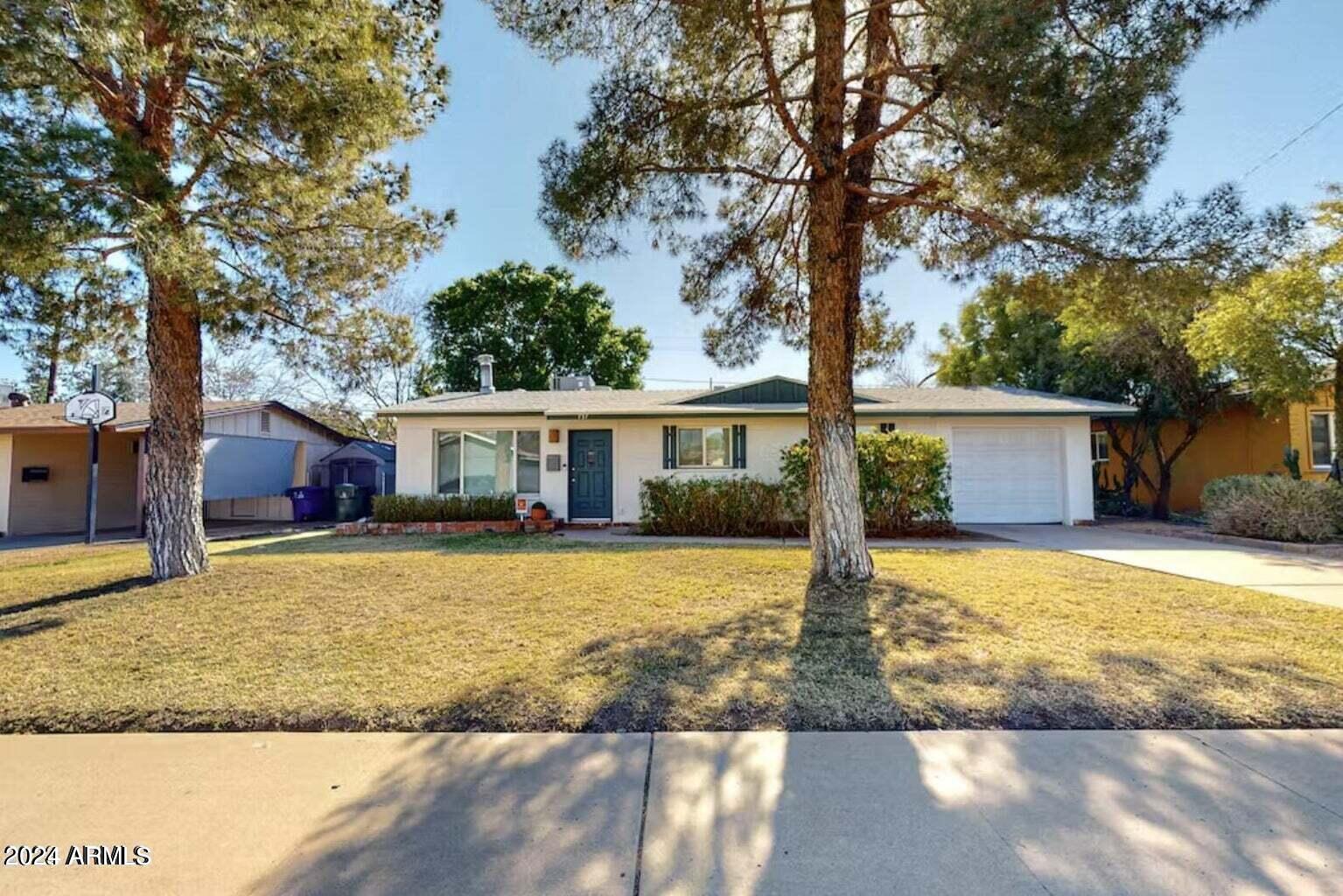 a front view of house with yard space and trees in the background