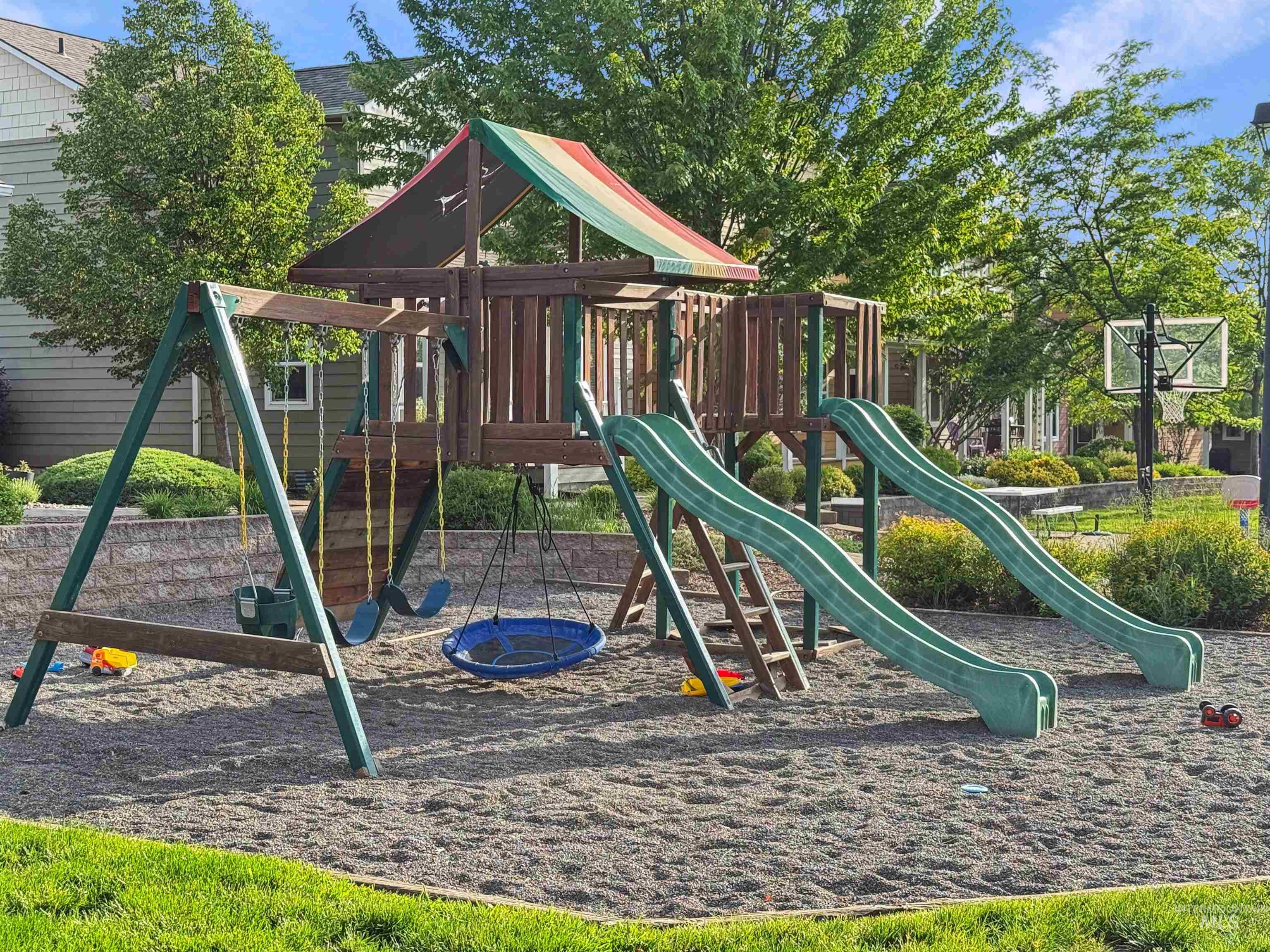 1354 Bristol Road Moscow, ID 83843 - Photo 17 of 19 Outdoor play structure featuring two green slides, multiple swings, and a raised play platform with a striped canopy