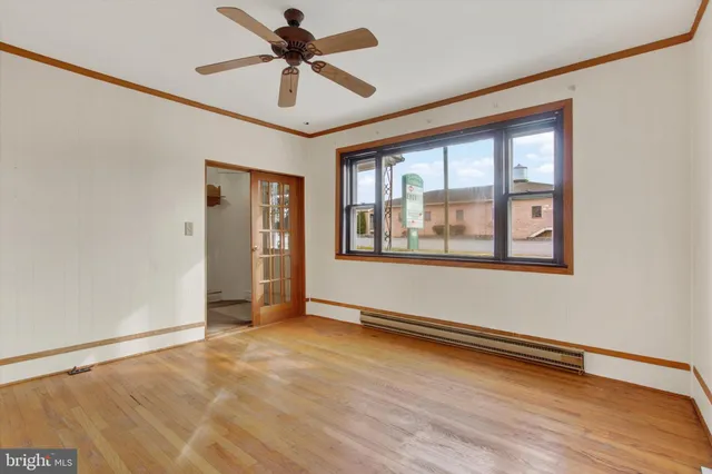 a view of an empty room with window and wooden floor