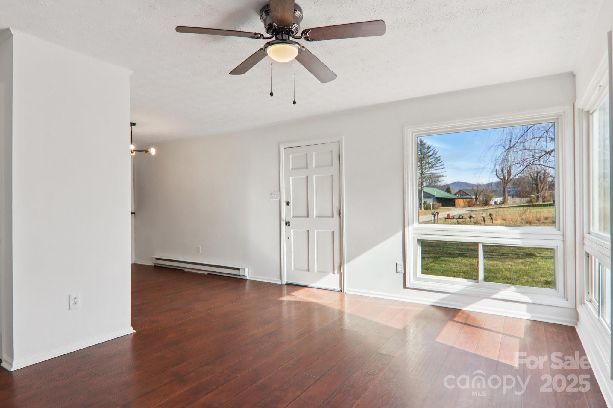 591 Blue Ridge Road Black Mountain, NC 28711 - Photo 3 of 32 an empty room with wooden floor fan and windows