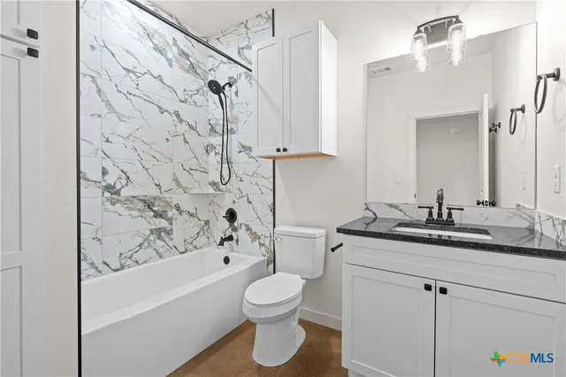 a bathroom with a granite countertop sink toilet a mirror a bathtub and shower