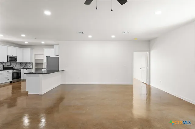 a view of kitchen with kitchen island white cabinets and stainless steel appliances