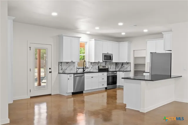 a kitchen with stainless steel appliances granite countertop a refrigerator sink and stove