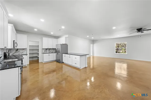 a view of kitchen with kitchen island a sink a stove and white cabinets