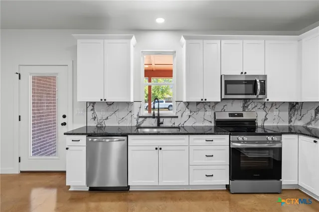 a kitchen with granite countertop white cabinets and stainless steel appliances