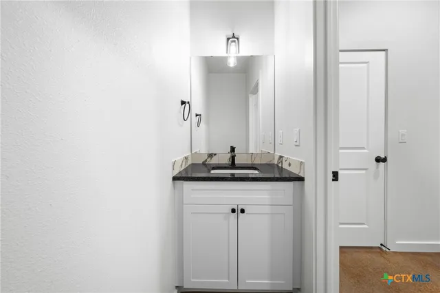 a bathroom with a granite countertop sink and a mirror