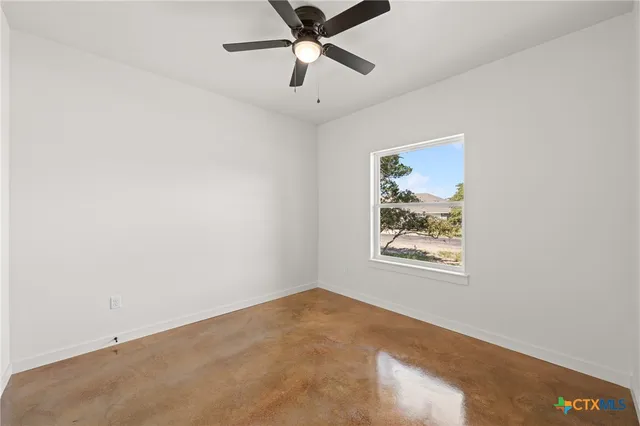 an empty room with a window and a ceiling fan