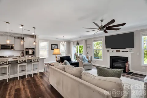 a living room with stainless steel appliances furniture a rug and a view of kitchen