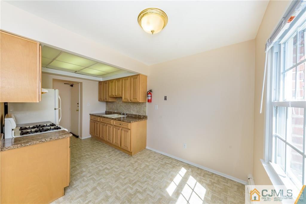 48 Stonehurst Boulevard, Unit E Freehold, NJ 07728 - Photo 9 of 15 a kitchen with granite countertop a stove a sink and a window