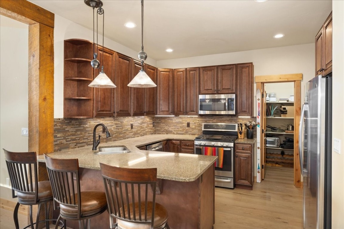 403 Fly Line Drive Silverthorne, CO 80498 - Photo 10 of 35 a kitchen with stainless steel appliances granite countertop a sink a stove a refrigerator cabinets and a dining table with wooden floor