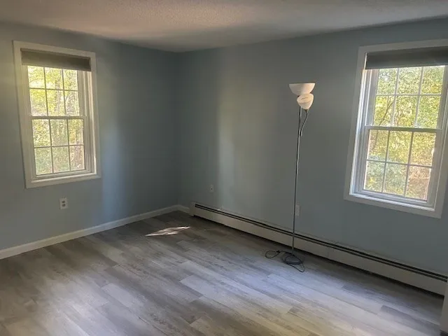 a view of an empty room with wooden floor and a window
