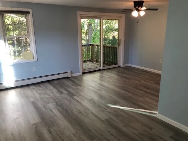 a view of an empty room with wooden floor and a window