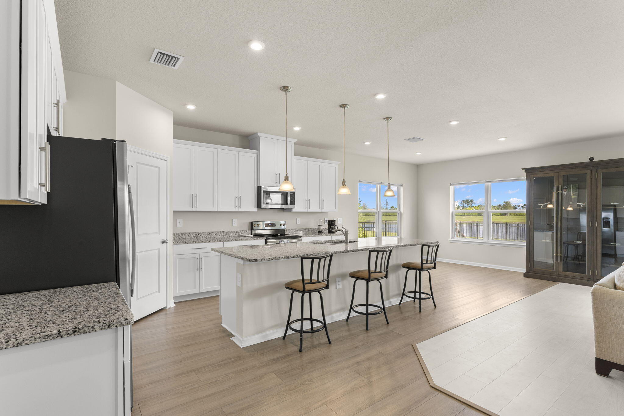 12291 Southwest Forli Way Port Port St. Lucie, FL 34987 - Photo 7 of 48 a kitchen with stainless steel appliances granite countertop a stove a refrigerator a sink a dining table and chairs with wooden floor