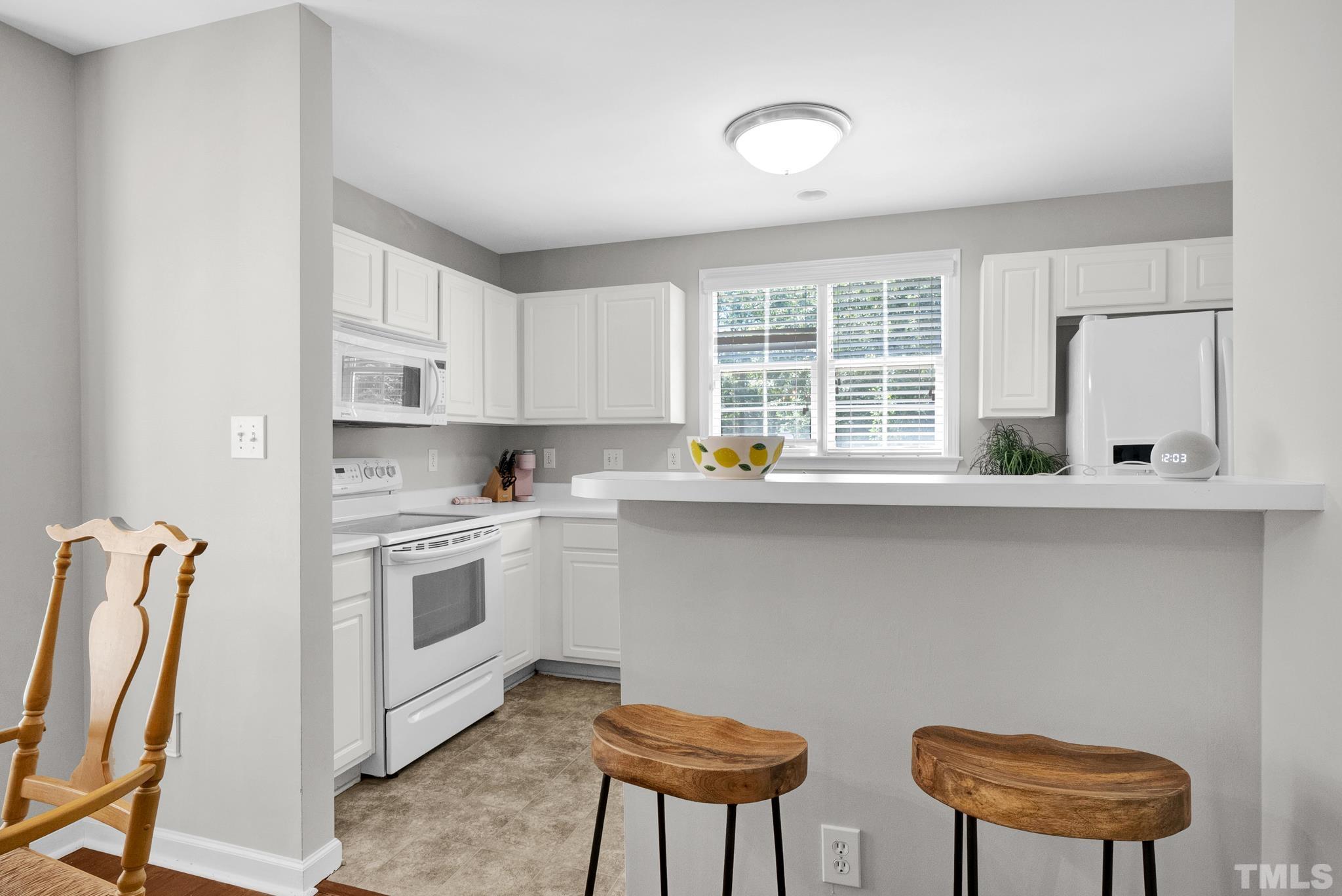 9553 Hanging Rock Road Raleigh, NC 27613 - Photo 7 of 36 a kitchen with stainless steel appliances a white stove top oven a sink a dining table and chairs with wooden floor