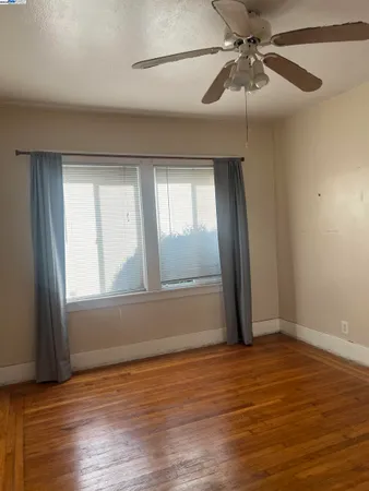 an empty room with wooden floor fan and windows